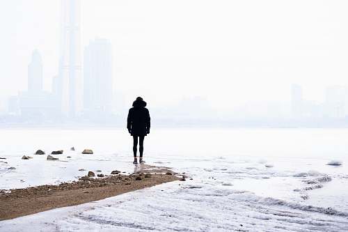 human person standing on seashore during daytime person