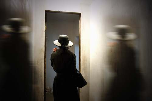 person person wearing hat carrying bag while standing in front of door hat