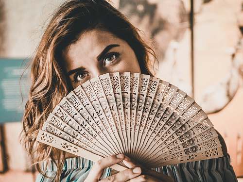 human photography of woman holding brown hand fan person