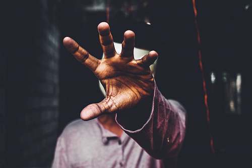 human selective focus photography of man raising his right hand during daytime person