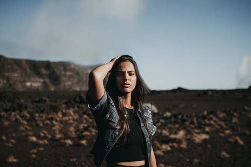 human selective focus photography of woman standing on black and brown field at daytime person