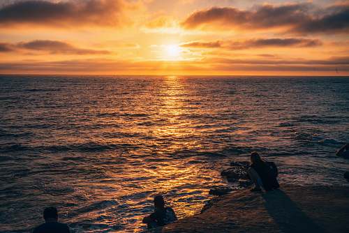 human silhouette of men in body of water during sunset person