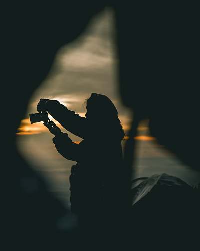human silhouette of person holding camera during orange sunset person