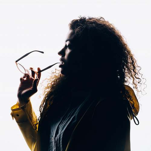 human silhouette photo of woman biting her eyeglasses person