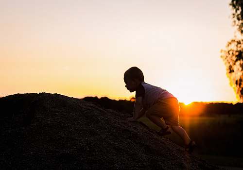 human silhouette photography of child climbing on rock person
