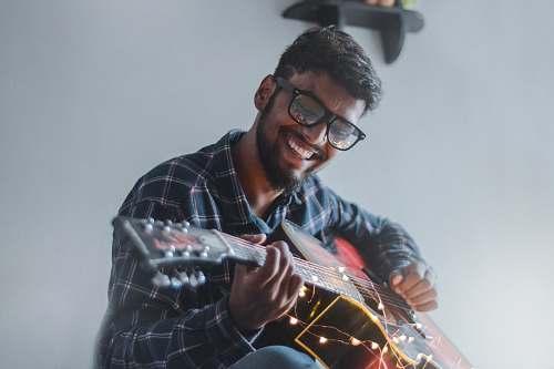 human smiling man sitting while playing guitar person