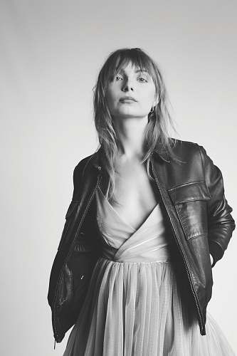 black-and-white standing woman with hands in jacket's pockets grey