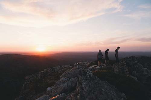 sunset three person standing on mountain during daytime sunrise