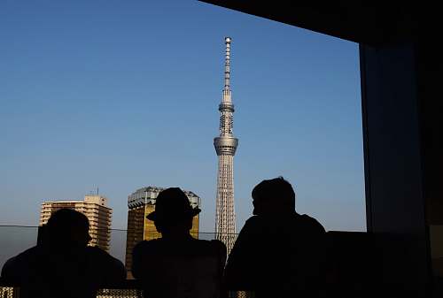 person three silhouette of persons standing in front window watching tower building human
