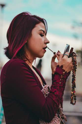 human tilt shift lens photography of woman pouring red lipstick on her lips person