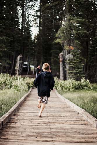person toddler running on brown wooden pathway human