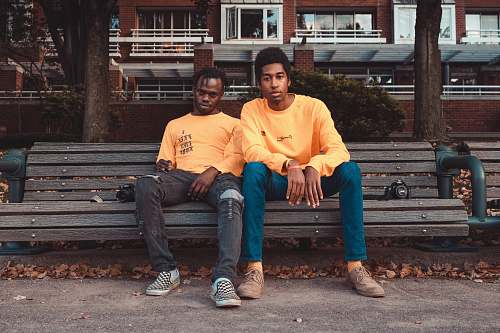 human two men's sitting on brown wooden bench chair person