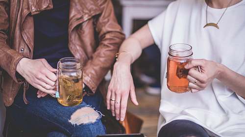drink two person sitting while holding clear glass mason mugs tea