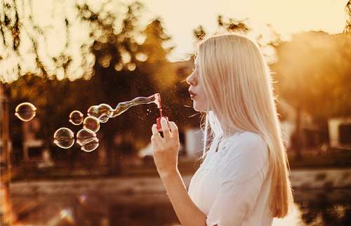 human woman blowing bubbles during sunset bubble