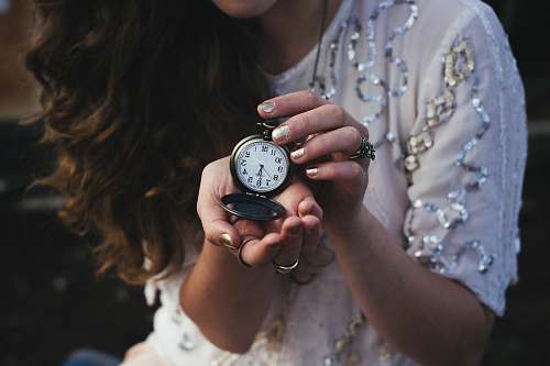 human woman holding black pocket watch at 5:30 time