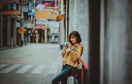 person woman holding camera while leaning on red handrail human