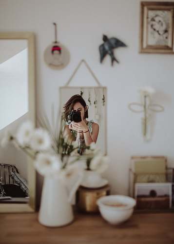 human woman holding DSLR camera taking photo in front mirror inside room person