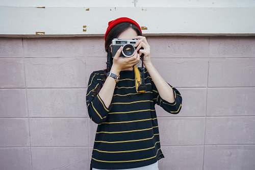 human woman holding DSLR camera while taking picture person