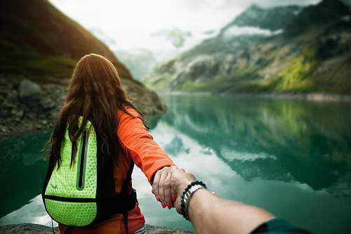 human woman holding man's hand in front of water person