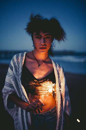 human woman holding sparkler standing near beach shore person