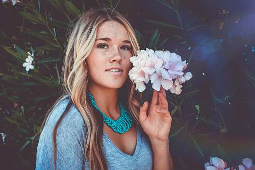 human woman holding the white flowers beside her face woman