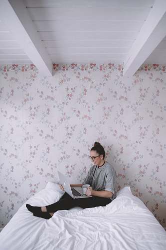 human woman holding white ceramic cup while using laptop person