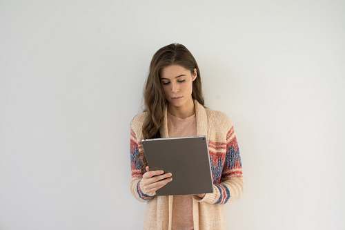 person woman in beige, gray, and red sweater holding silver tablet computer human