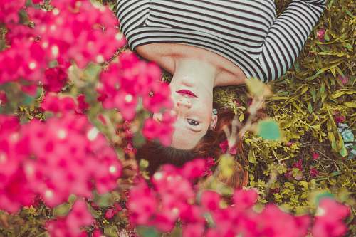 person woman in black and white striped top lying on grass face