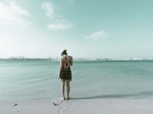 beach woman in black outfit standing on beach sand coast