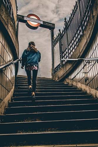 person woman in blue denim button-up jacket walking on concrete stairs during daytime london