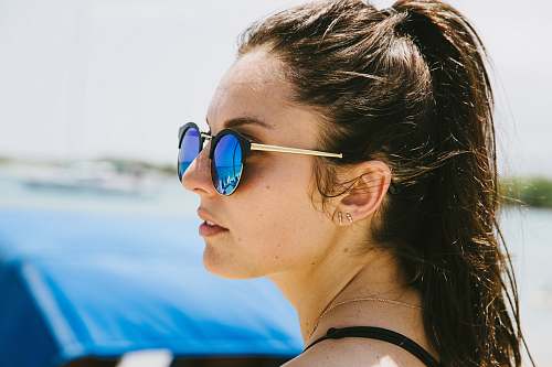 human woman in blue sunglasses in front of blue car during daytime shallow focus photography person
