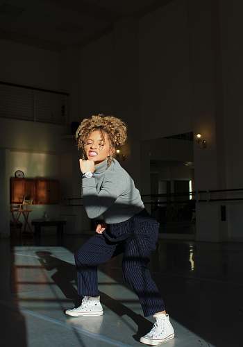 human woman in grey turtleneck sweater and pinstripe pants squatting person