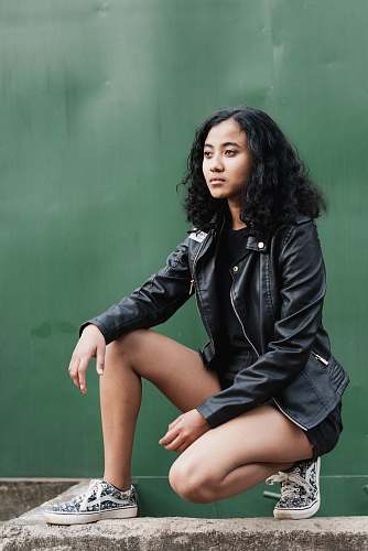 human woman in squat position on front of green wall person