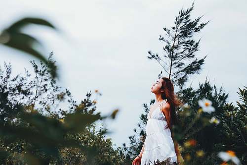 person woman in white deep V-neck sleeveless dress surrounded with plants female