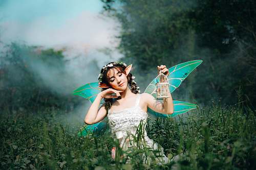 human woman in white dress wearing green fairy wings person
