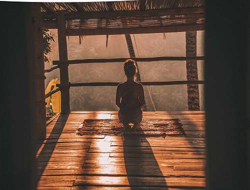 yoga woman meditating on floor with overlooking view of trees bali