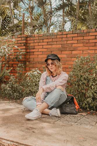person woman sitting down on gray concrete slab near brick wall human