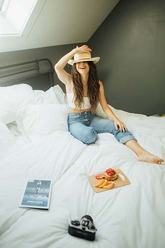 human woman sitting on bed holding her hat person