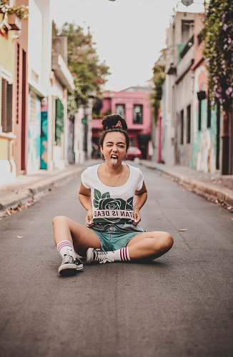 human woman sitting on road with pair of shoes at daytime person
