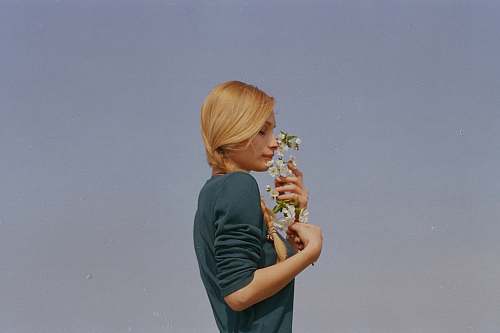 human woman smelling white petaled flowers person