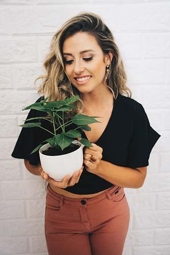 human woman smiling while holding potted plant person