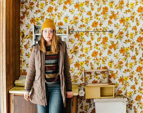 human woman standing near cabinet in front of floral wallpaper person