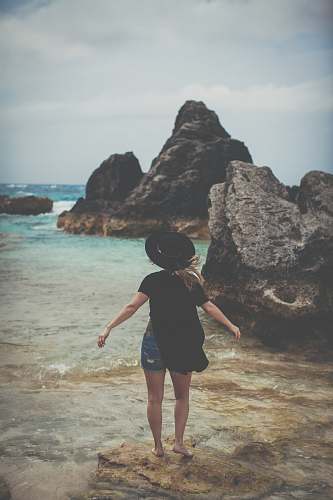 human woman standing on rock near ocean shoreline person
