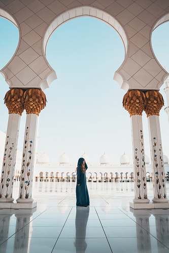 person woman standing on white tiled floor in the middle of concrete pillars building