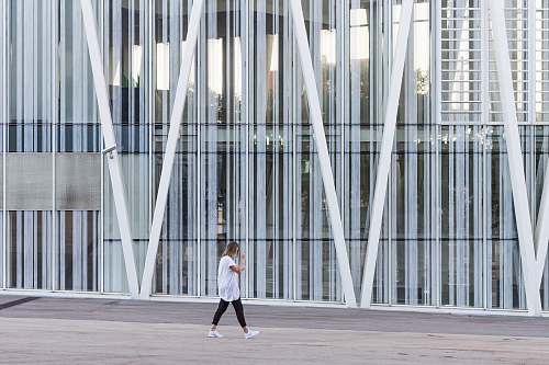 human woman walking beside white painted building taken at daytime person