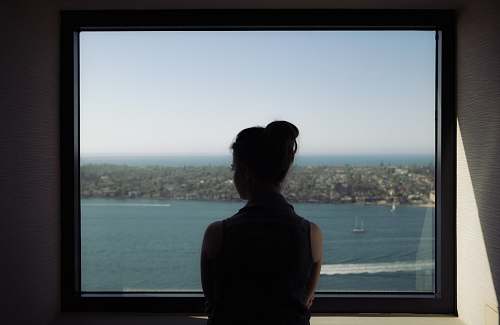 person woman wearing off-shoulder shirt standing beside window human