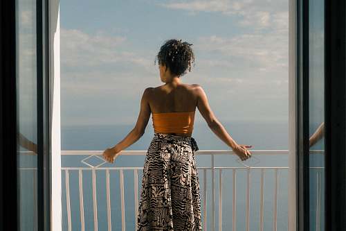 human woman wearing orange tube and black skirt facing terrace person