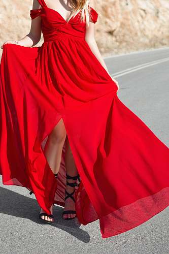 human woman wearing red cold-shoulder front-slit formal dress standing on road person