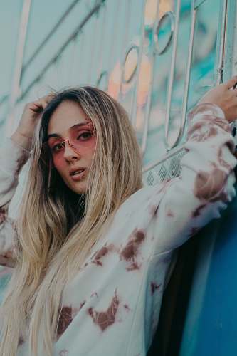 human woman wearing white and brown long-sleeved shirt leaning on grey metal railings person