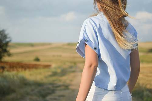 human woman wearing white dress shirt standing on green grass field during day time person
